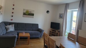 A living room with a sofa, a coffee table, a TV stand, and a dining table with chairs. - Vacation apartments Meyer, between Nuremberg and Ansbach A6/B14, near Playmobil Fun Park (Heilsbronn)