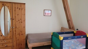 A bedroom with a wooden wardrobe, a bed, and a child’s playpen. - Vacation apartments Meyer, between Nuremberg and Ansbach A6/B14, near Playmobil Fun Park (Heilsbronn)