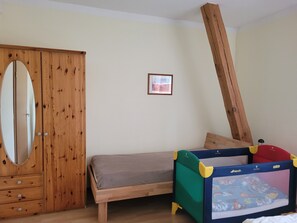 A bedroom with a wooden wardrobe, a bed, and a child’s playpen. - Vacation apartments Meyer, between Nuremberg and Ansbach A6/B14, near Playmobil Fun Park (Heilsbronn)
