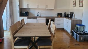 A modern kitchen with white cabinets, a wooden dining table, and a built-in oven. - Vacation apartments Meyer, between Nuremberg and Ansbach A6/B14, near Playmobil Fun Park (Heilsbronn)