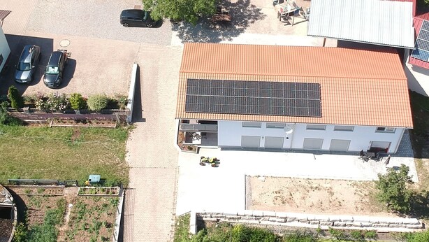 An aerial view of a residential area with multiple houses, a paved driveway, and a solar panel installation on one of the buildings. - Vacation apartments Meyer, between Nuremberg and Ansbach A6/B14, near Playmobil Fun Park (Heilsbronn)