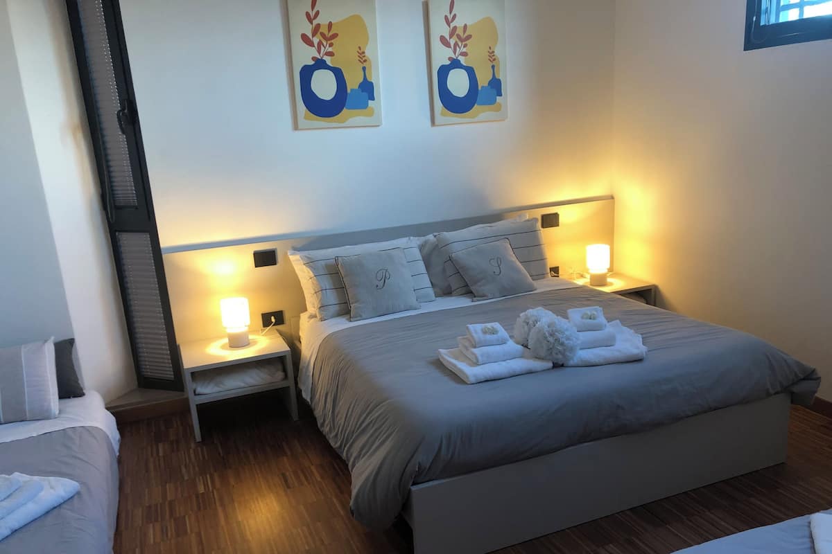 A neatly arranged hotel room with a large bed, two bedside tables with lamps, and a headboard with a built-in shelf.