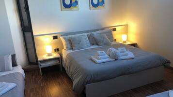Une chambre d’hôtel bien aménagée, avec un grand lit, deux tables de chevet équipées de lampes et une tête de lit dotée d’une étagère intégrée.