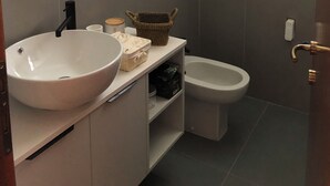A bathroom with a white sink, a mirror, a toilet, and a shower area. - Il piccolo scrigno  (Lonigo)