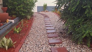 A pathway with stepping stones leading to a building, surrounded by gravel and plants. - Charming 2-bedroom apartment with WiFi, AC in pleasant Westmoorings (Diego Martin Regional Corporation)