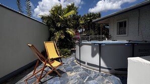 A patio with a pool, a lounge chair, and a stone-tiled floor. - Charming 2-bedroom apartment with WiFi, AC in pleasant Westmoorings (Diego Martin Regional Corporation)