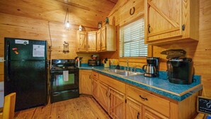 A kitchen with wooden cabinets, a refrigerator, an oven, a microwave, a sink, and a coffee maker.