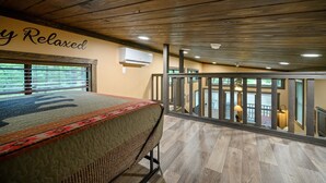 Une chambre avec un grand lit, un plafond en bois et un balcon doté d’une balustrade.