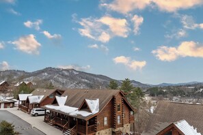 A log cabin-style hotel with a snow-covered roof, a covered porch, and a view of mountains in the background. - Luxury Pigeon Forge Condo  Near Dollywood & Parks (Pigeon Forge)