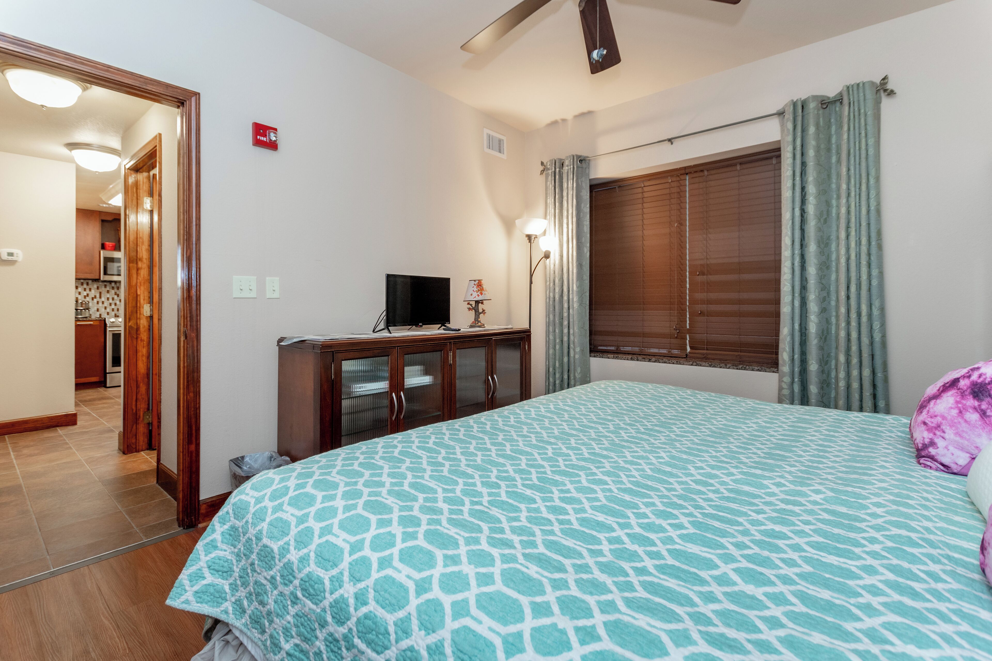 A bedroom with a bed, a TV, a cabinet, and a window with curtains.