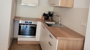 A compact kitchen with white cabinets, a built-in oven, a wooden countertop, and a sink. - Vacation apartments Meyer, between Nuremberg and Ansbach A6/B14, near Playmobil Fun Park (Heilsbronn)