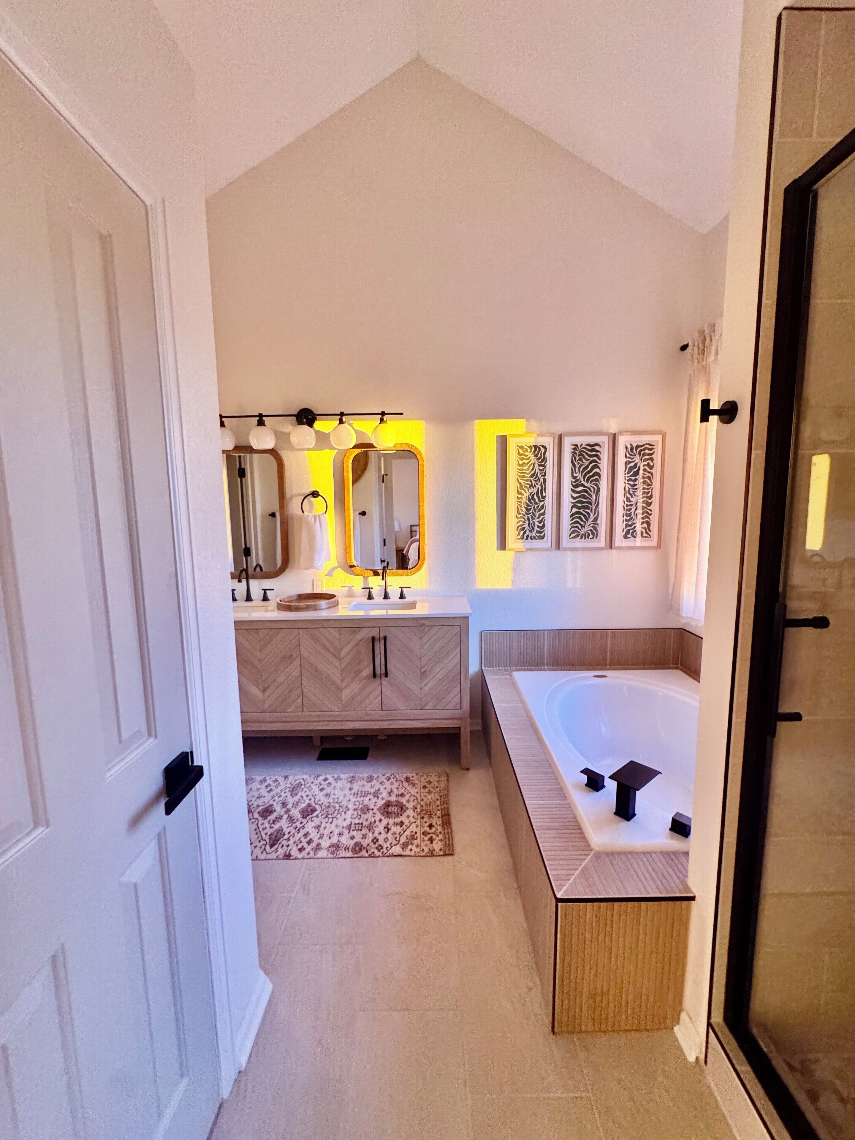 A modern bathroom with a freestanding bathtub, a vanity with a mirror, and a shower area.