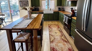 Uma cozinha espaçosa com piso de madeira, uma grande mesa de jantar e armários verdes.