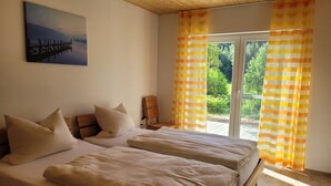 Ein Schlafzimmer mit zwei Betten, einem Bild an der Wand und einem Fenster mit Vorhängen.