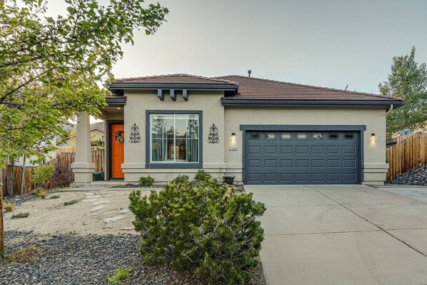 A single-story house with a garage, a front door, and a small front yard with a gravel path and a potted plant. - 3BR 2BA, MTN view, relaxing yard (Reno)