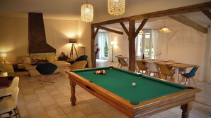 A cozy room with a pool table, comfortable seating, and a dining area.