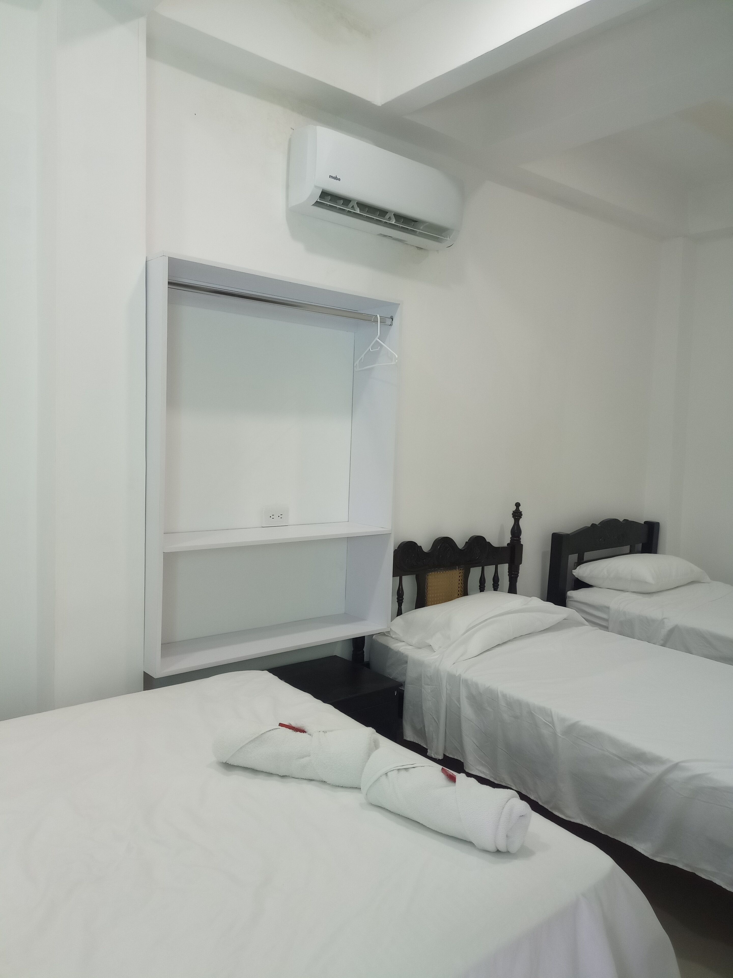 A hotel room with two single beds, a wardrobe, and an air conditioning unit.