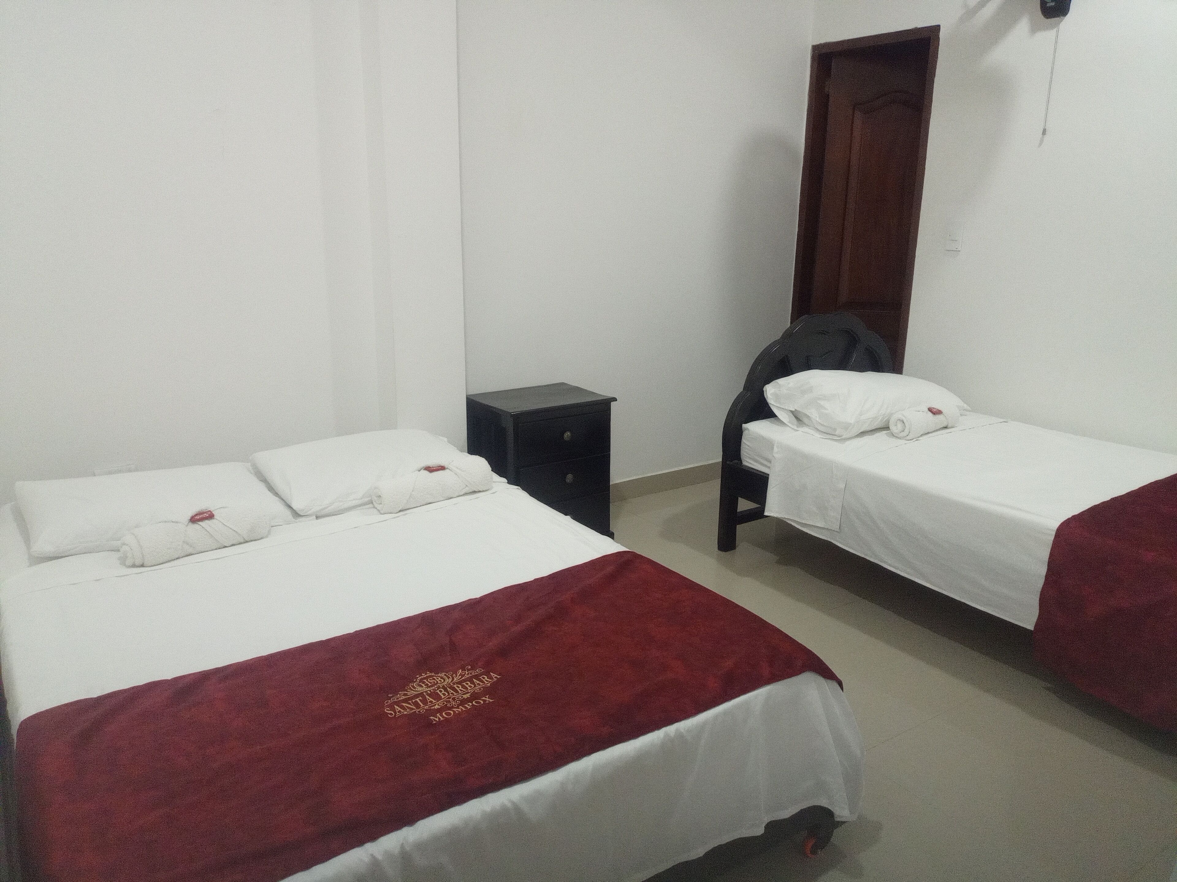 A hotel room with two single beds, a small bedside table, a wardrobe, and a door.