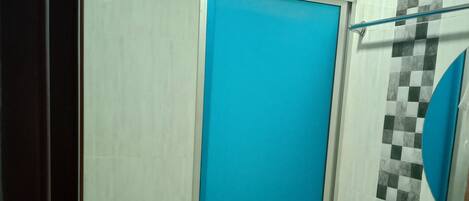 Ein Badezimmer mit weißer Toilette, einer blauen Duschkabine und einer Wand mit Schachbrettmuster-Fliesen.