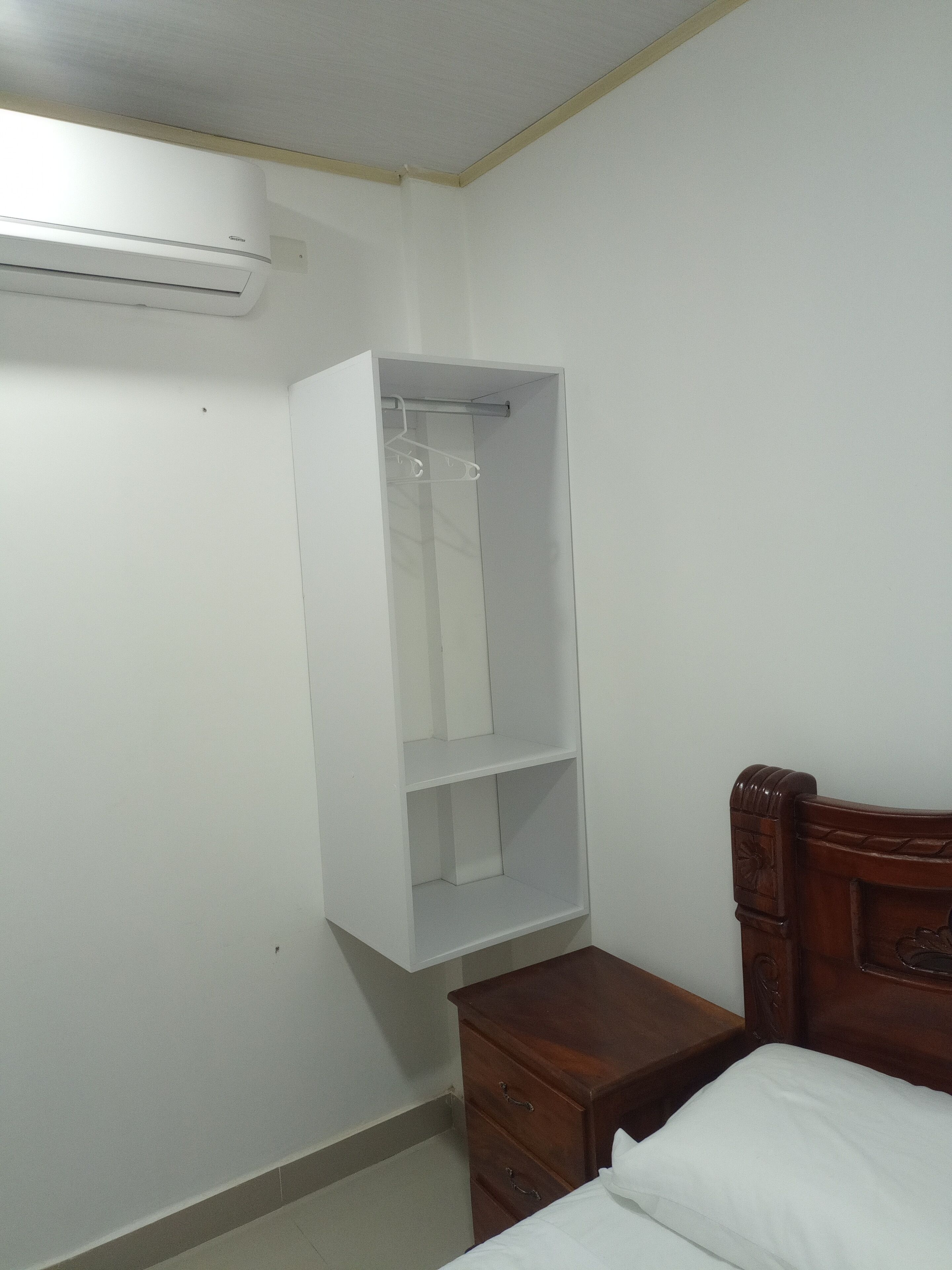 Un dormitorio con una cama de madera, un armario blanco y una mesita de noche de madera.