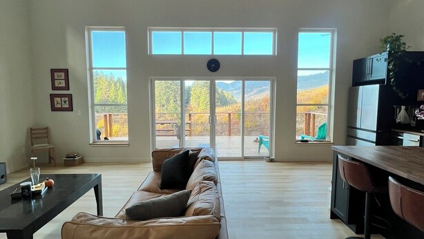 Amplia sala de estar con un ventanal grande, un sofá, una zona de comedor y una cocina.