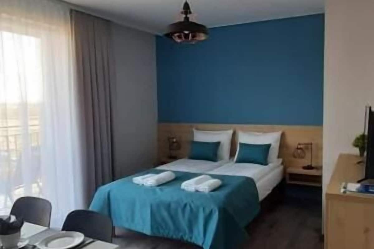 A hotel room with a bed, a desk, and a chair.