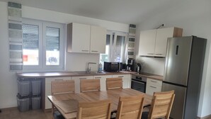 Eine moderne Küche mit einem Holzespeisetisch, Stühlen, einem Kühlschrank und einer Mikrowelle.