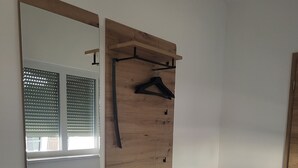 Ein Zimmer mit einer hölzernen Bank, einem Spiegel und einem Wandregal mit Kleiderhängern.