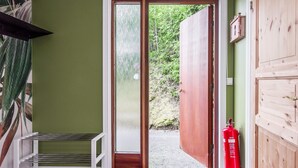 Une porte donnant sur un jardin, avec un extincteur fixé au mur.