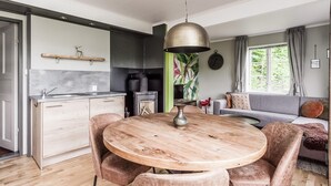 Une cuisine moderne avec une table de salle à manger ronde en bois, un four encastré et un luminaire suspendu.