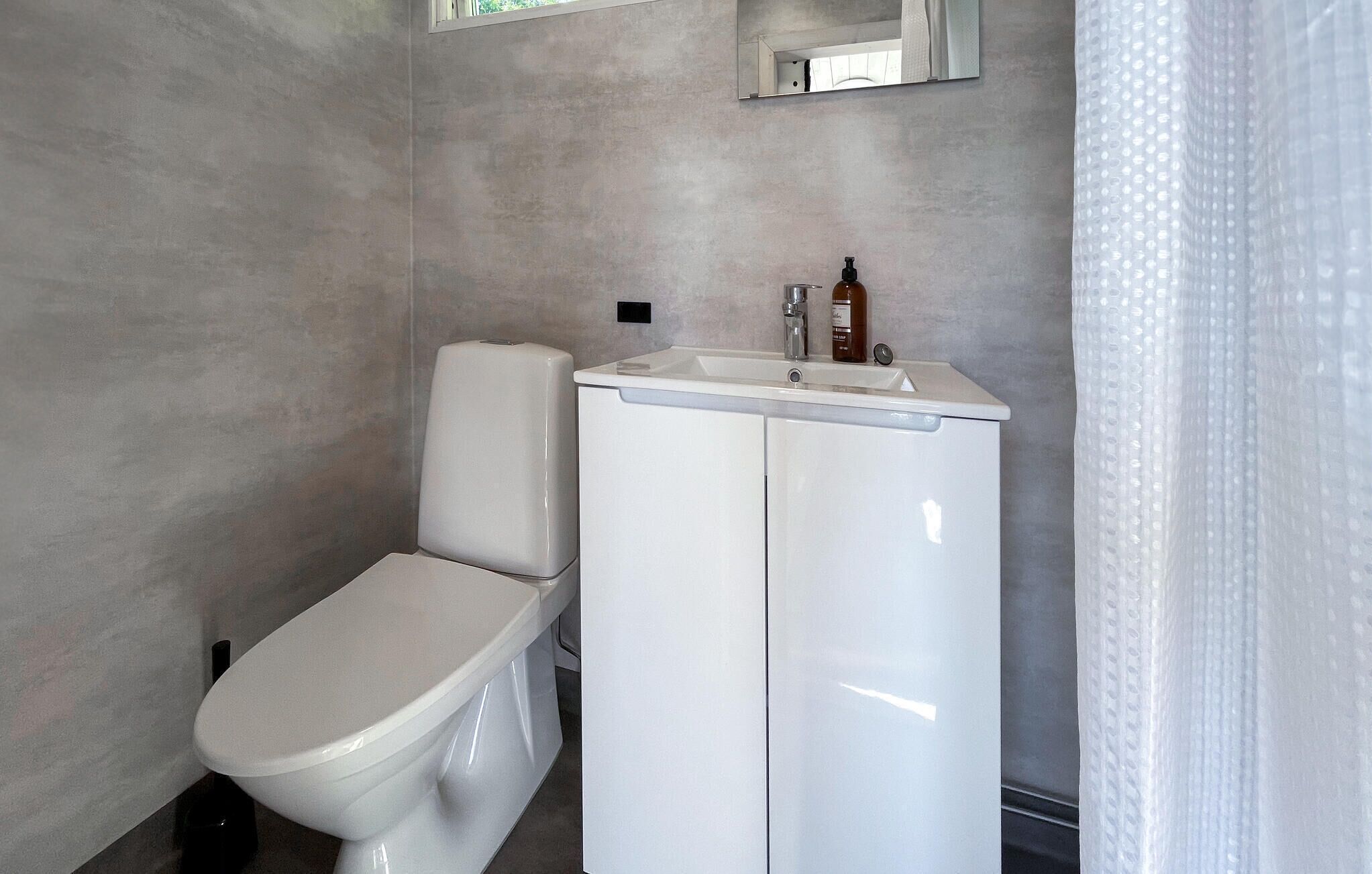 Un baño pequeño con inodoro, lavamanos y espejo.