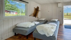 A room with two grey beds, a wooden ceiling, and a large window with a view of a red building and greenery outside. - Stunning home in Laholm with WiFi (Laholm)
