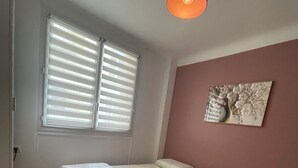 A room with two beds, a ceiling light, a window with blinds, and a wall-mounted artwork. - Paris Montparnasse Alesia Plaisance, Café and restaurant, near center 2mn metro (Paris)