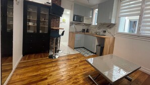 A compact kitchen with a wooden floor, a dining table, and a built-in microwave. - Paris Montparnasse Alesia Plaisance, Café and restaurant, near center 2mn metro (Paris)