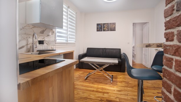 A compact kitchen with a marble countertop, a black leather sofa, and a dining area with a chair. - Paris Montparnasse Alesia Plaisance, Café and restaurant, near center 2mn metro (Paris)