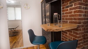 A room with a wooden table, two blue chairs, a black cabinet, and a brick wall. - Paris Montparnasse Alesia Plaisance, Café and restaurant, near center 2mn metro (Paris)