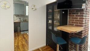 A compact kitchen with a wooden floor, a black cabinet with glass doors, and a small wooden table with two blue chairs. - Paris Montparnasse Alesia Plaisance, Café and restaurant, near center 2mn metro (Paris)