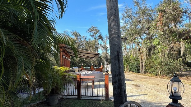 Un espace patio agrémenté d’une pergola en bois, d’un barbecue et d’une enseigne indiquant un restaurant nommé « Middelle Chandelle ».