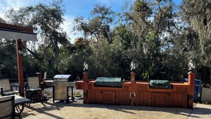 Une terrasse extérieure avec un barbecue, des sièges et une clôture en bois.