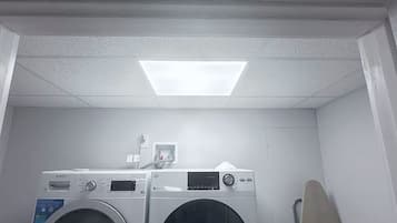 A laundry room with two front-loading washing machines and a dryer.