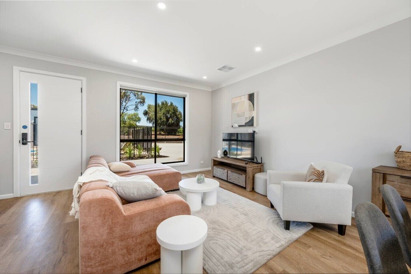 A modern living room with a sofa, armchairs, a coffee table, and a TV.