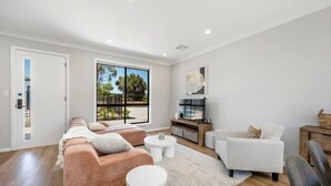 Een moderne woonkamer met een bank, fauteuils, een salontafel en een televisie.