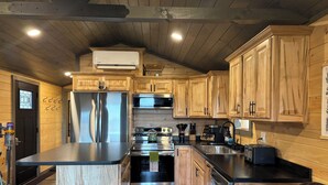 Una cocina moderna con gabinetes de madera, electrodomésticos de acero inoxidable y encimera negra.