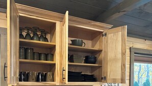 Una cocina con armarios de madera, un tostador, un lavavajillas y una ventana con vistas a árboles.