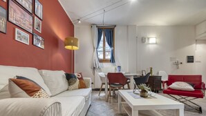 Ett modernt vardagsrum med en vit soffa, en röd fåtölj och ett matbord med stolar.