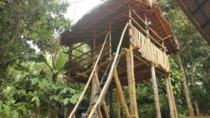 A bamboo structure with a ladder, surrounded by dense foliage. - Wayanad days Holiday Home with Tree Hut and Tent

 (Mananthavady)