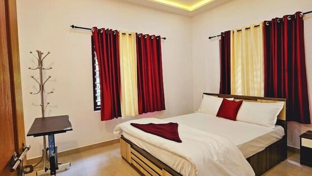 A hotel room with a bed, a coat rack, and curtains. - Wayanad days Holiday Home with Tree Hut and Tent

 (Mananthavady)