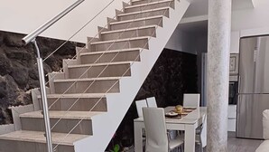 Une cuisine moderne dotée d’un réfrigérateur encastré, d’un coin repas avec une table et des chaises, et d’un escalier avec une rampe en métal.