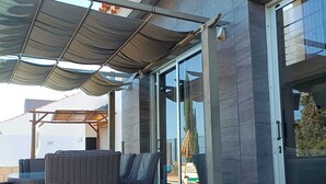 Un espace extérieur aménagé, abrité et doté de meubles en osier et d’une pergola.