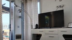 Une cuisine moderne dotée d’un téléviseur encastré, d’une horloge murale et d’un espace douche séparé par des rideaux.
